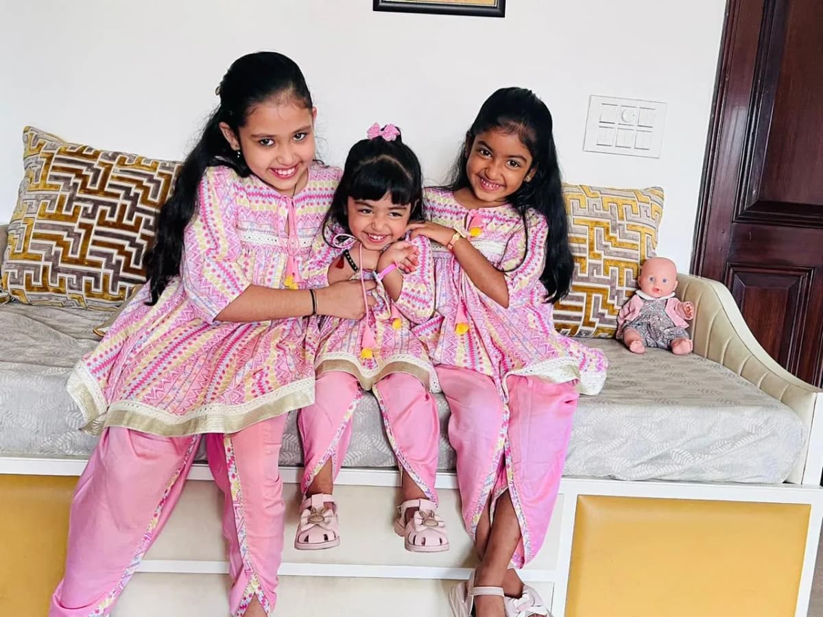 Three girls in matching pink printed kurta sets sitting together