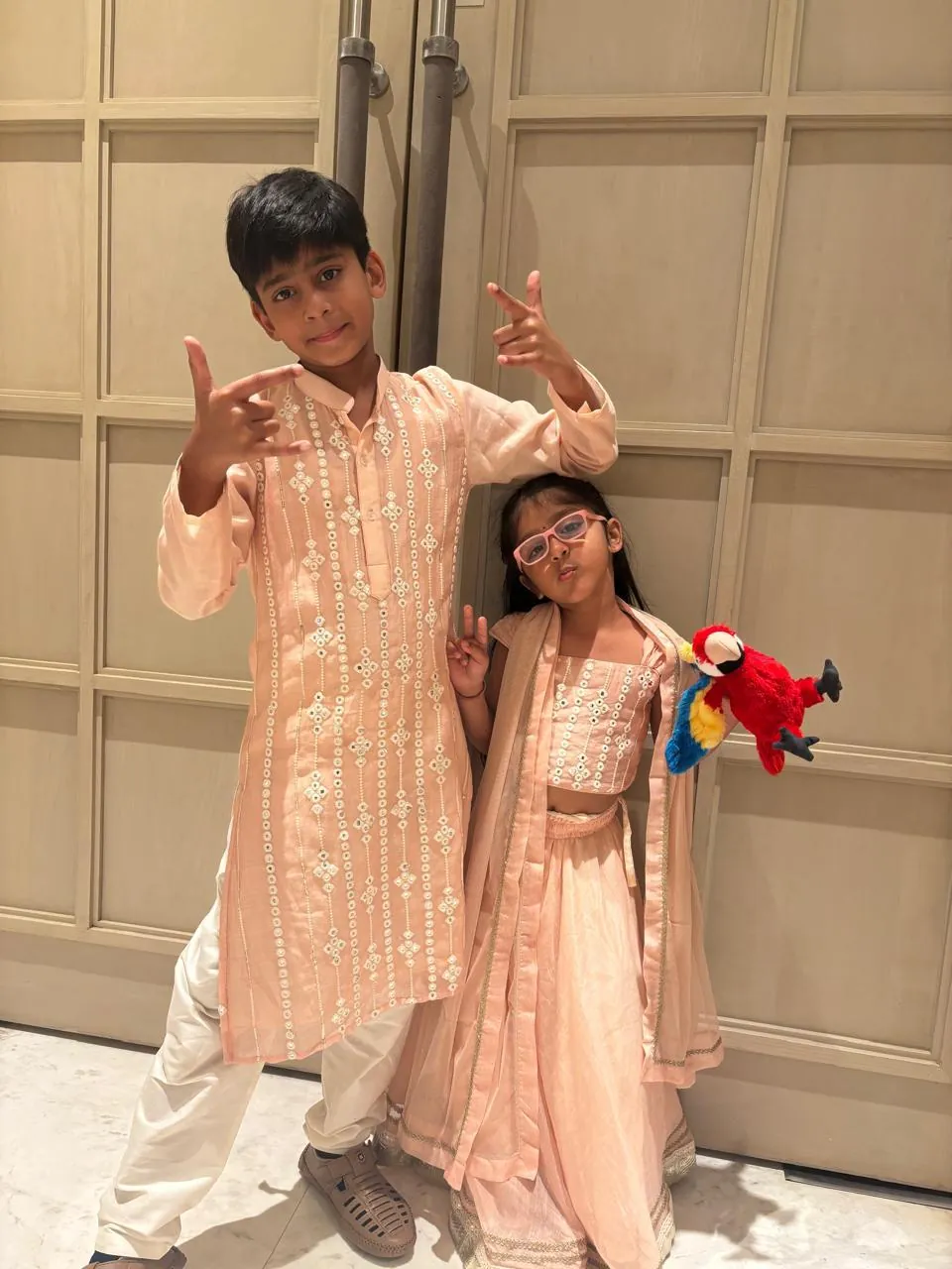 Boy in a peach embroidered kurta and girl in a peach lehenga posing together